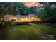 Backyard with a well-manicured lawn and mature trees at sunset at 9439 White Hemlock Ln, Charlotte, NC 28270