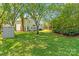 Expansive backyard with lush greenery, mature trees, a shed, and a view of the home's exterior at 111 Woodfern Pl, Mooresville, NC 28115