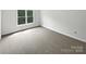 An empty bedroom space featuring neutral carpet and a sunlit window at 1121 Setter Se Ln, Concord, NC 28025