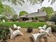 Backyard featuring in-ground fire pit with modern white chairs, garden, and luxurious home at 1126 Concord Rd, Davidson, NC 28036