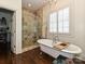 Elegant bathroom featuring a soaking tub and glass-enclosed marble shower with wooden floors and a chandelier at 1126 Concord Rd, Davidson, NC 28036