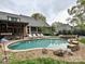 In-ground pool and hot tub with stone surround, deck chairs, and covered patio area at 1126 Concord Rd, Davidson, NC 28036