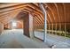 A spacious unfinished attic with exposed wooden beams and a brick chimney at 113 S College St, Monroe, NC 28112