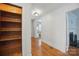A well-lit hallway with an open closet door and hardwood flooring with a view of a fireplace at 113 S College St, Monroe, NC 28112