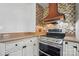 Close up of the kitchen stove with a copper vent hood and mosaic tile backsplash at 113 S College St, Monroe, NC 28112