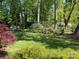 A verdant backyard oasis with lush greenery and mature trees with a small bridge at 121 General Pemberton St, Stanley, NC 28164