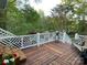 Wooden deck highlighting decorative railing and a serene view of a flower-filled landscape with mature trees at 121 General Pemberton St, Stanley, NC 28164