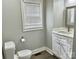 A neat bathroom with a toilet and vanity near a window providing natural light at 121 W 11Th St, Oakboro, NC 28129
