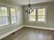 Sunny living room featuring three large windows, hardwood floors, and a decorative chandelier at 121 W 11Th St, Oakboro, NC 28129