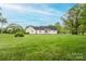 Lush green backyard with white house exterior, complete with brick patio and mature trees at 123 Coachman Loop, Statesville, NC 28625