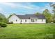 Green backyard with patio, white exterior, and mature trees, creating a tranquil outdoor space at 123 Coachman Loop, Statesville, NC 28625