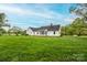 Lush green backyard with white exterior, including brick patio and sunroom, enhanced by mature trees at 123 Coachman Loop, Statesville, NC 28625