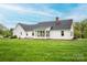 Expansive green backyard with the white house, brick patio, and mature trees offering a serene view at 123 Coachman Loop, Statesville, NC 28625