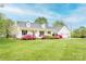 Charming white home with a covered front porch and colorful landscaping in a large, well-manicured yard at 123 Coachman Loop, Statesville, NC 28625
