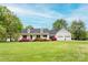 Beautiful white home featuring a welcoming front porch, lush landscaping, and an attached two-car garage at 123 Coachman Loop, Statesville, NC 28625