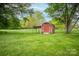 Red storage shed in lush green backyard, surrounded by trees, providing extra outdoor space at 123 Coachman Loop, Statesville, NC 28625