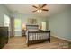 Bedroom with wood-look floors, a bed with a floral quilt, a ceiling fan, and natural light from the surrounding windows at 12435 Mallard Dr, Charlotte, NC 28269