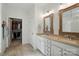 Bright bathroom featuring double sinks, walk-in closet, neutral tile flooring, and decorative framed mirrors at 12512 Journeys End Trl, Huntersville, NC 28078