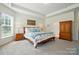 Spacious bedroom with tray ceiling, wooden furniture, and plenty of natural light from multiple windows at 12512 Journeys End Trl, Huntersville, NC 28078