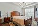 Bedroom with wooden bed frame, two side tables with lamps, chandelier, and large window at 12512 Journeys End Trl, Huntersville, NC 28078