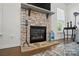 Close-up of a stone fireplace with a black mantel, flanked by windows and stylish decor at 12512 Journeys End Trl, Huntersville, NC 28078