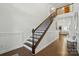 Staircase with decorative wood and iron railing, white wainscoting, and hardwood floors at 12512 Journeys End Trl, Huntersville, NC 28078