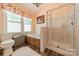 Bathroom with a glass-enclosed shower and soaking tub; floral valances on the window allow natural light to brighten the space at 14926 Chilgrove Ln, Huntersville, NC 28078