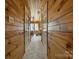 Hallway featuring wood paneled walls and a view into a sunlit room, creating a warm and inviting atmosphere at 14926 Chilgrove Ln, Huntersville, NC 28078