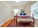 Cozy bedroom with hardwood floors, bright light, and a traditional bed with a red-and-blue blanket at 1943 S Wendover Rd, Charlotte, NC 28211
