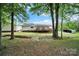 Landscaped backyard with a large deck with access ramp, and a shed with a carport surrounded by mature trees and lush green grass at 1981 Line Rd, Lancaster, SC 29720