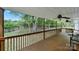 View from home’s covered wooden deck highlighting the railing, ceiling fans, and the lush backyard with mature trees at 1981 Line Rd, Lancaster, SC 29720