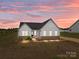 Charming exterior of a single-story home with white siding, black roof, and manicured front yard at sunset at 210 Goldenrod Cir, Salisbury, NC 28147
