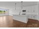 Bright kitchen boasts white cabinetry, modern appliances, island with quartz countertops, and hardwood floors at 210 Goldenrod Cir, Salisbury, NC 28147