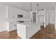Bright kitchen boasts white cabinetry, modern appliances, island with quartz countertops, and hardwood floors at 210 Goldenrod Cir, Salisbury, NC 28147