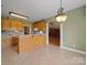 Open kitchen with tiled floors, wooden cabinets, and a decorative light fixture overlooking the adjacent living spaces at 514 Clover Leaf Rd, Marshville, NC 28103