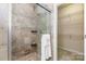 Luxurious walk-in shower featuring designer tile, rainfall shower head and bench seating at 5283 Fieldstone Dr, Concord, NC 28025