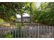 A cozy home seen through a picket fence, nestled among mature trees with a bench inviting you to relax and enjoy the view at 539 Marsh Rd, Charlotte, NC 28209