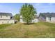 The backyard features a lush lawn, framed by mature trees for serene outdoor living at 6135 Raisin Tree Ln, Charlotte, NC 28215