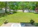 Spacious backyard with green grass, white fence, mature trees, a storage shed, and a picnic table at 6622 Cedar Cliff Dr, Charlotte, NC 28216