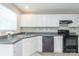Functional kitchen features white cabinets and black appliances at 6622 Cedar Cliff Dr, Charlotte, NC 28216