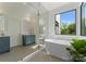 Bright bathroom boasts a soaking tub, blue vanity, and seamless glass shower at 721 Charles Ave, Charlotte, NC 28205