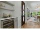 Hallway with wine fridge, shelving, and glass doors leading to back porch at 721 Charles Ave, Charlotte, NC 28205