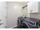 Modern laundry room featuring front-load washer/dryer and white cabinets at 7239 Oxford Hunt Dr, Stanley, NC 28164