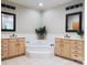 Bright bathroom featuring dual vanities, a jetted tub, neutral tile flooring, and elegant fixtures at 7626 Vistaview Dr, Cornelius, NC 28031