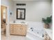 Well-lit bathroom showcasing a vanity, soaking tub, decorative tiles, and a door to an adjacent room at 7626 Vistaview Dr, Cornelius, NC 28031