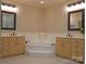 Bathroom showcasing dual sink vanities, a soaking tub with tile surround, and decorative lighting at 7626 Vistaview Dr, Cornelius, NC 28031