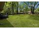 Spacious backyard with lush lawn, mature trees, and a deck for outdoor enjoyment at 801 Bilmark Ave, Charlotte, NC 28213
