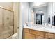 Bathroom with a marble countertop vanity, wood cabinets, a large mirror, and a glass-enclosed shower at 9200 Kingsmead Ln, Waxhaw, NC 28173