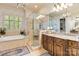 Bathroom featuring granite countertop vanity, a separate shower with glass door, and a soaking tub by a window at 9200 Kingsmead Ln, Waxhaw, NC 28173