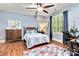 Cozy bedroom featuring hardwood floors, a ceiling fan, and a double window dressed with blue curtains at 9200 Kingsmead Ln, Waxhaw, NC 28173